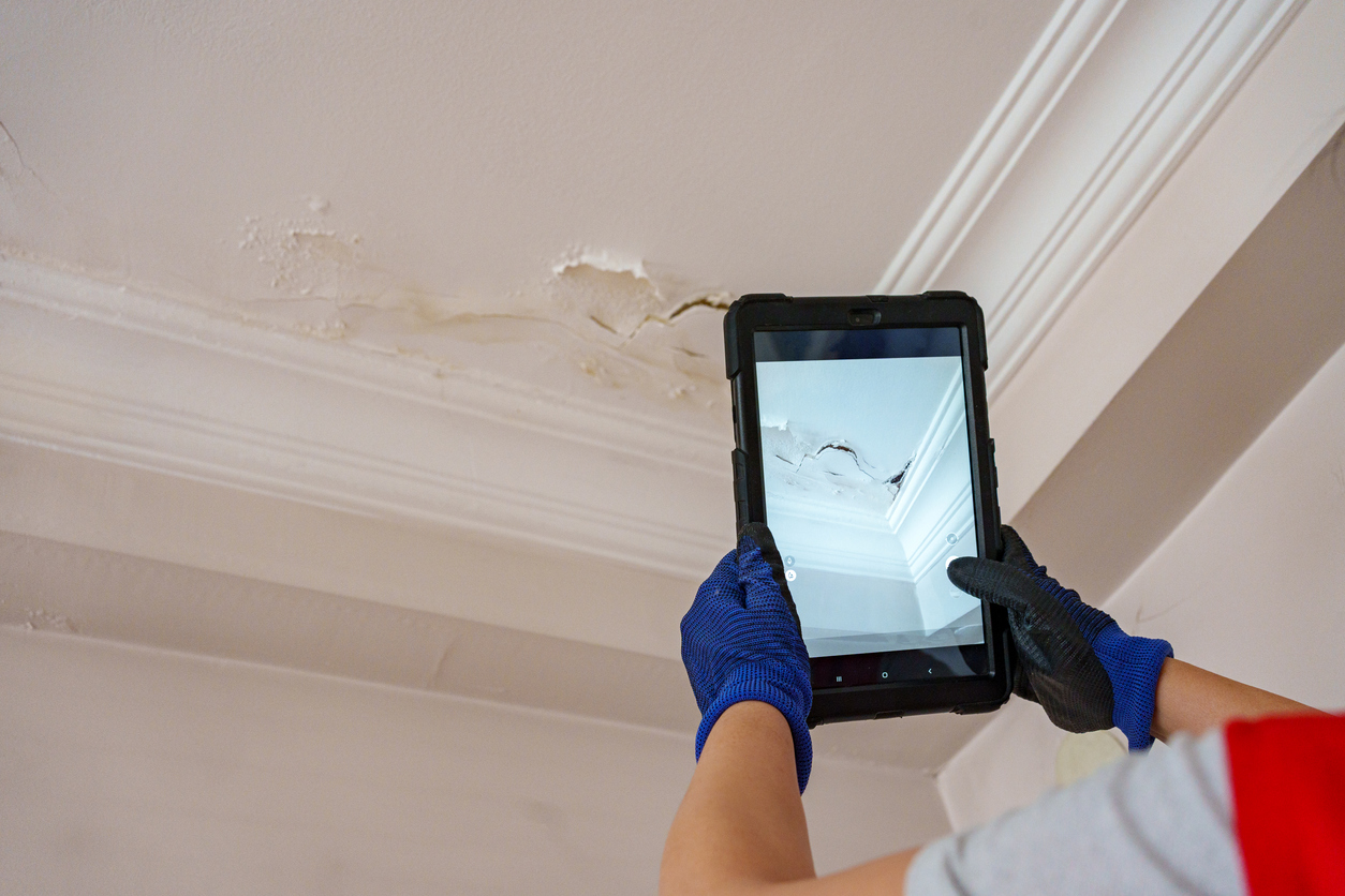 Homeowner documenting water damage with a phone for insurance claim